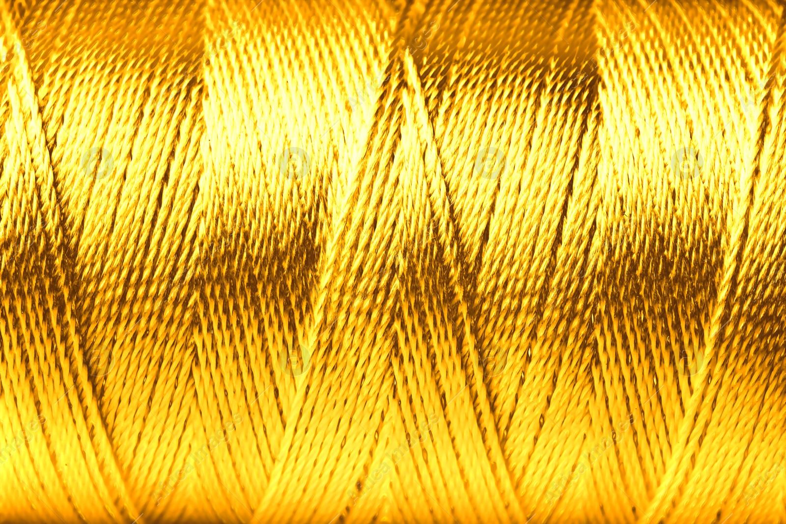 Image of Spool of golden sewing thread as background, closeup