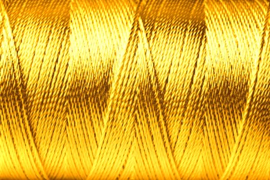 Image of Spool of golden sewing thread as background, closeup