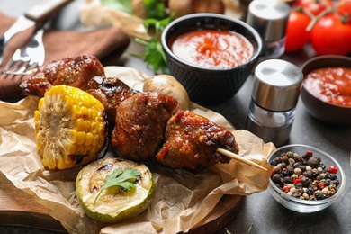 Photo of Delicious meat and vegetables served for barbecue party on gray table