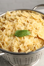 Photo of Cooked pasta in metal colander on grey table, closeup