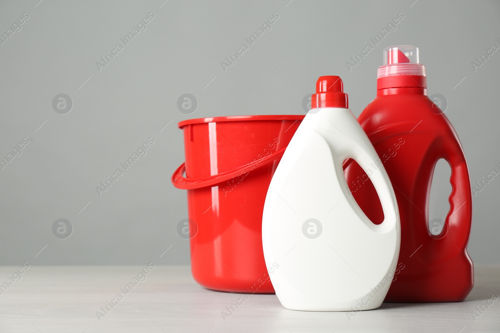 Photo of Bucket and cleaning products on grey table. Space for text