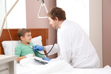 Photo of Doctor examining little child with stethoscope in hospital