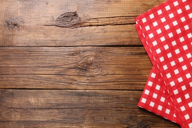 Photo of Red checkered tablecloth on wooden table, top view. Space for text
