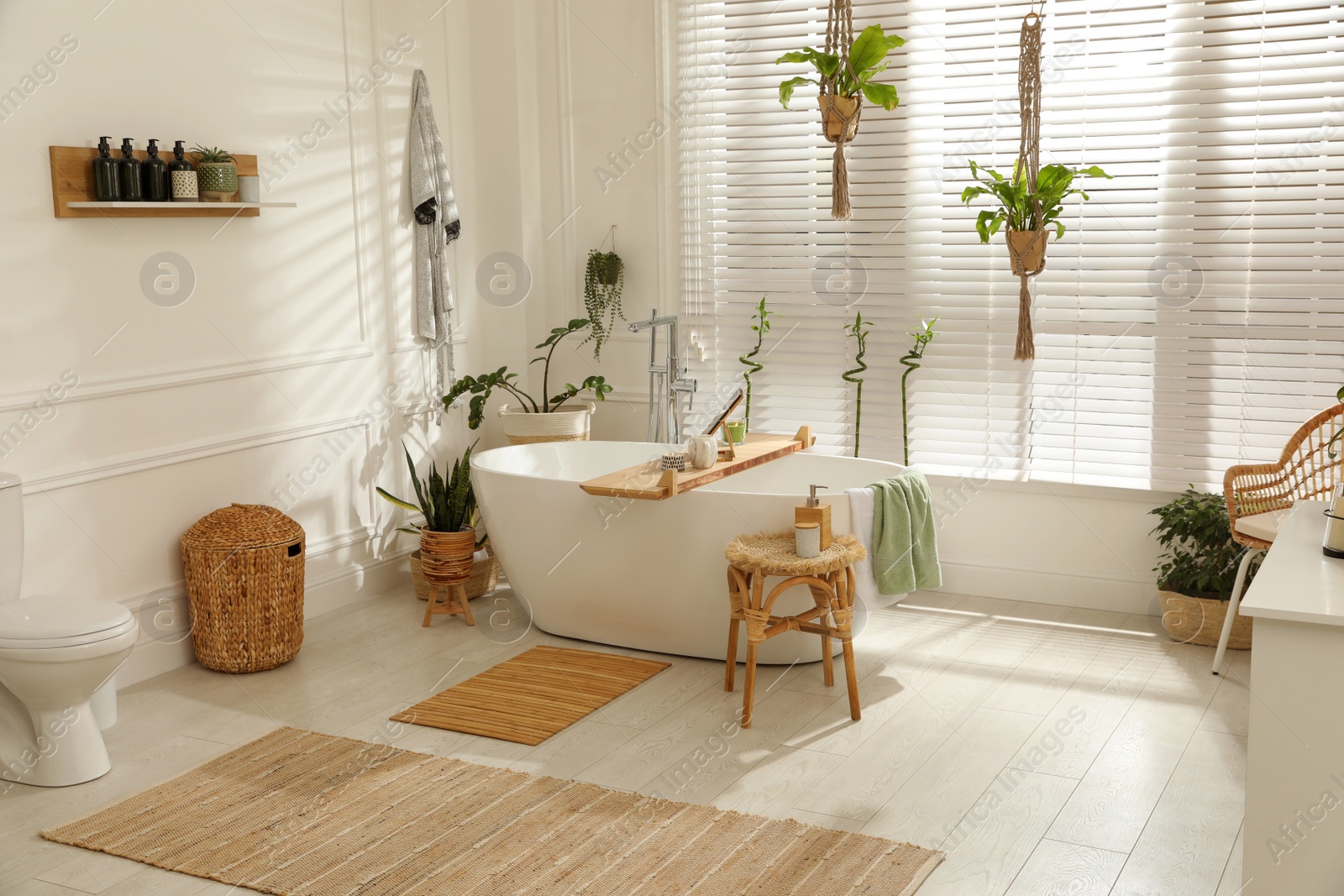 Photo of Stylish white tub and green houseplants in bathroom. Interior design