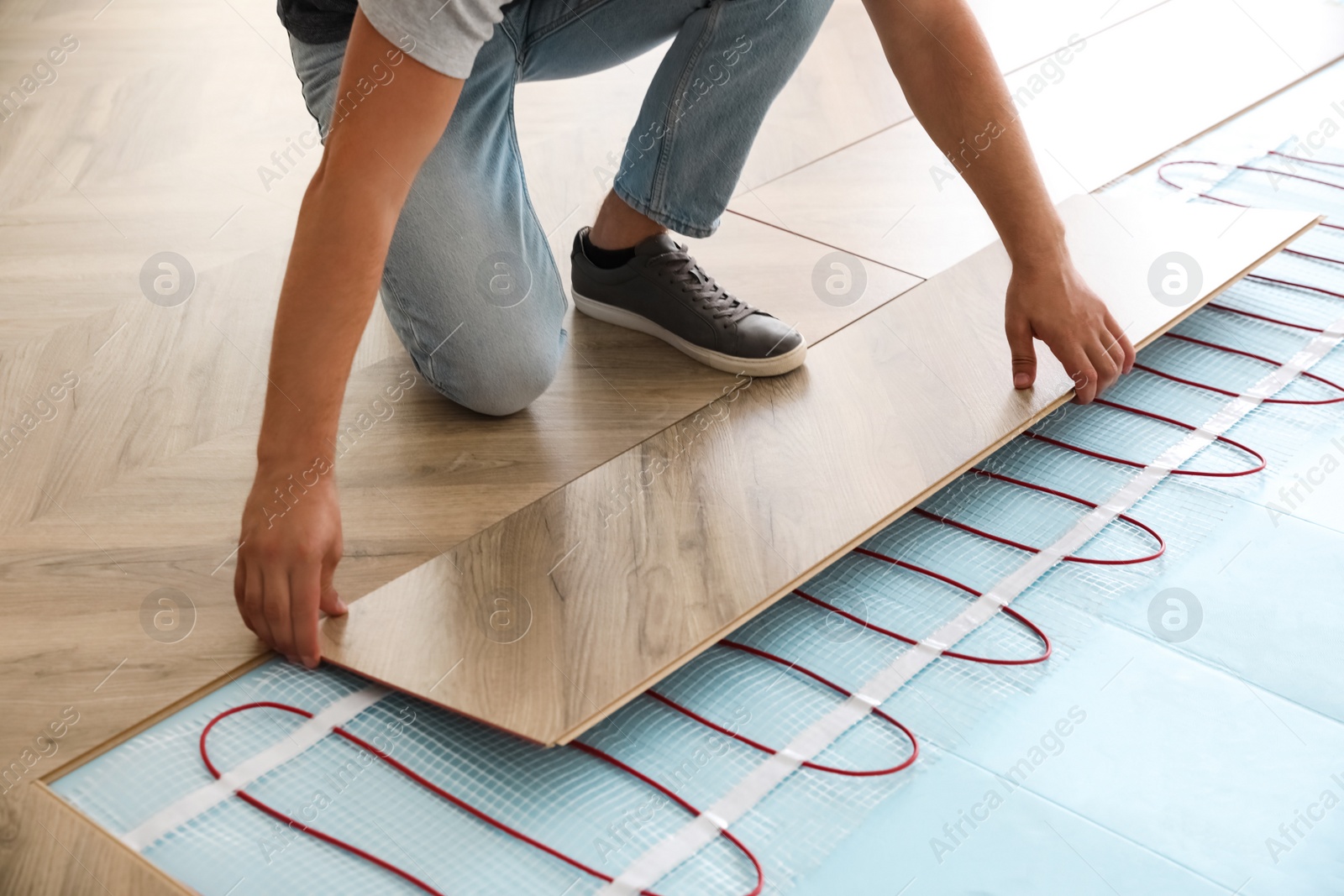 Photo of Professional contractor installing underfloor trace heating system indoors, closeup