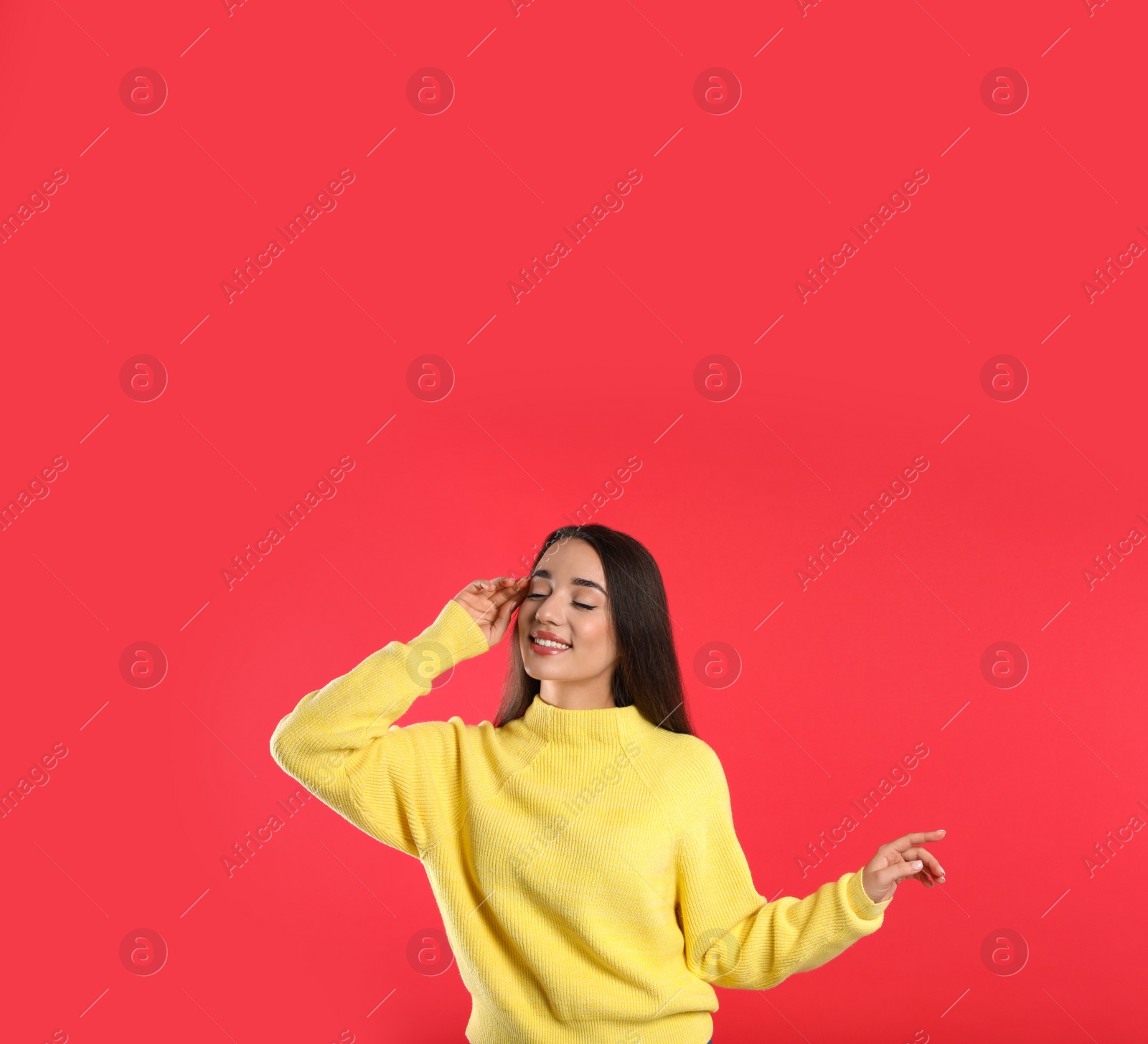 Photo of Beautiful young woman wearing yellow warm sweater on red background