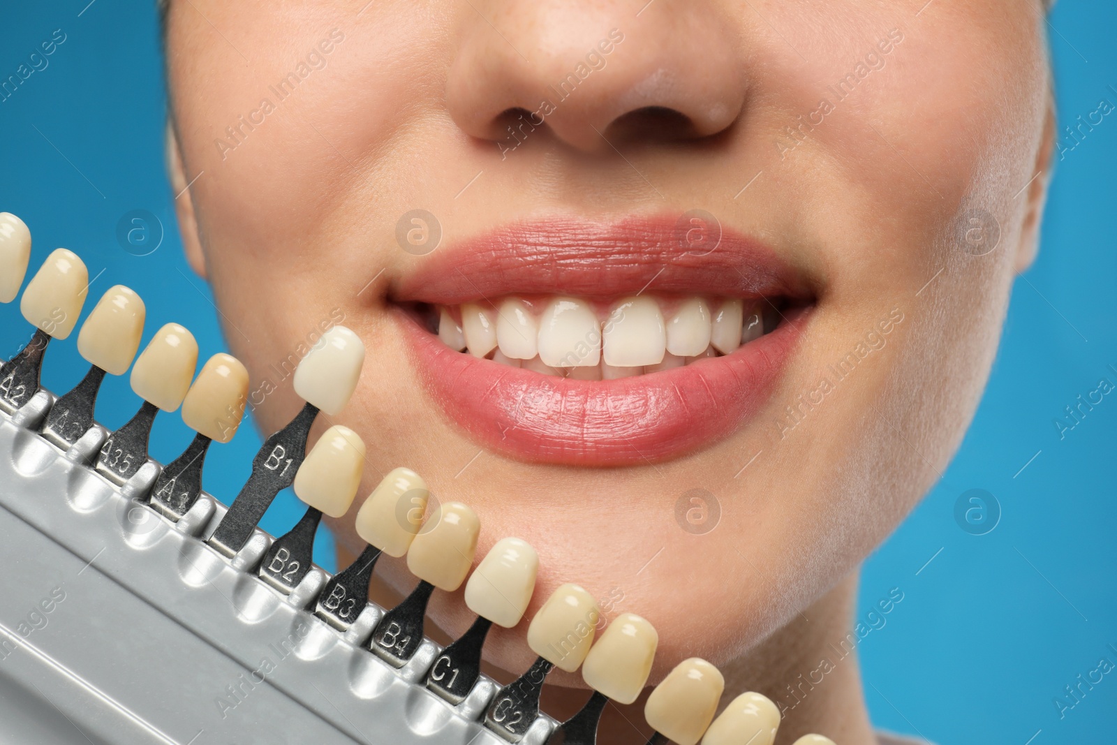 Photo of Woman checking her teeth color on blue background, closeup. Cosmetic dentistry