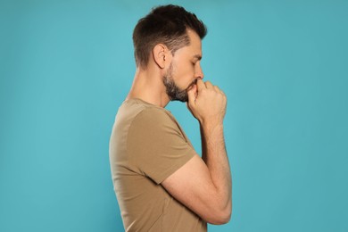 Photo of Man with clasped hands praying on turquoise background