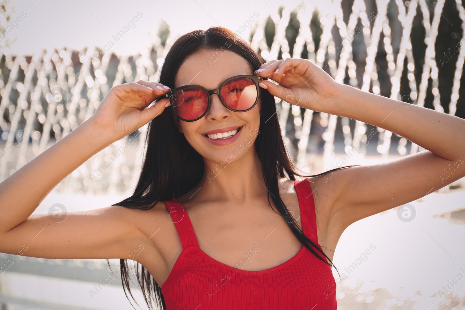 Photo of Beautiful young woman wearing stylish sunglasses outdoors