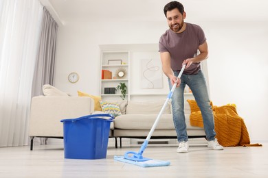 Spring cleaning. Man with mop washing floor at home