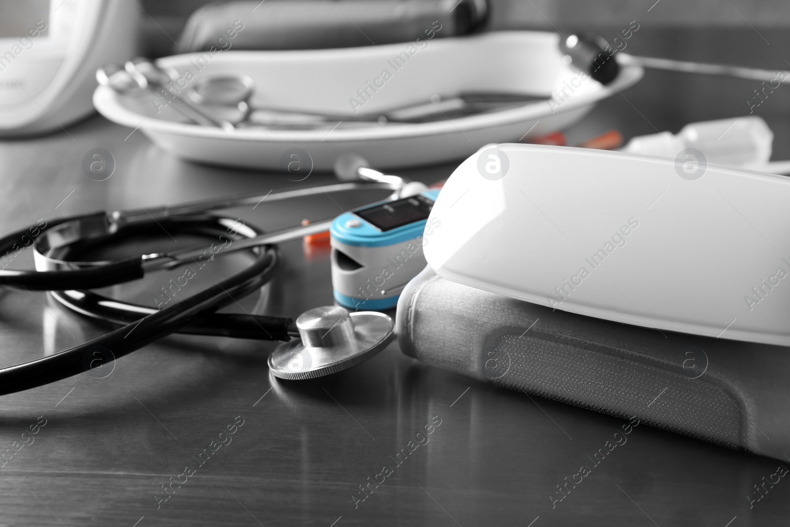 Photo of Sphygmomanometer, stethoscope and blood pressure monitor on grey table. Medical objects