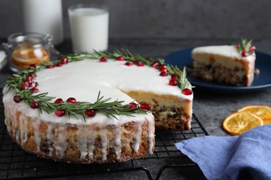 Photo of Traditional Christmas cake decorated with rosemary and pomegranate seeds on grey table