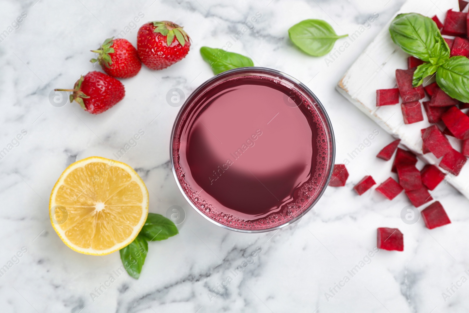 Photo of Glass with fresh juice and ingredients on marble table, top view