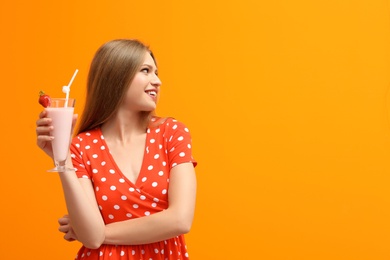 Young woman with glass of delicious milk shake on color background