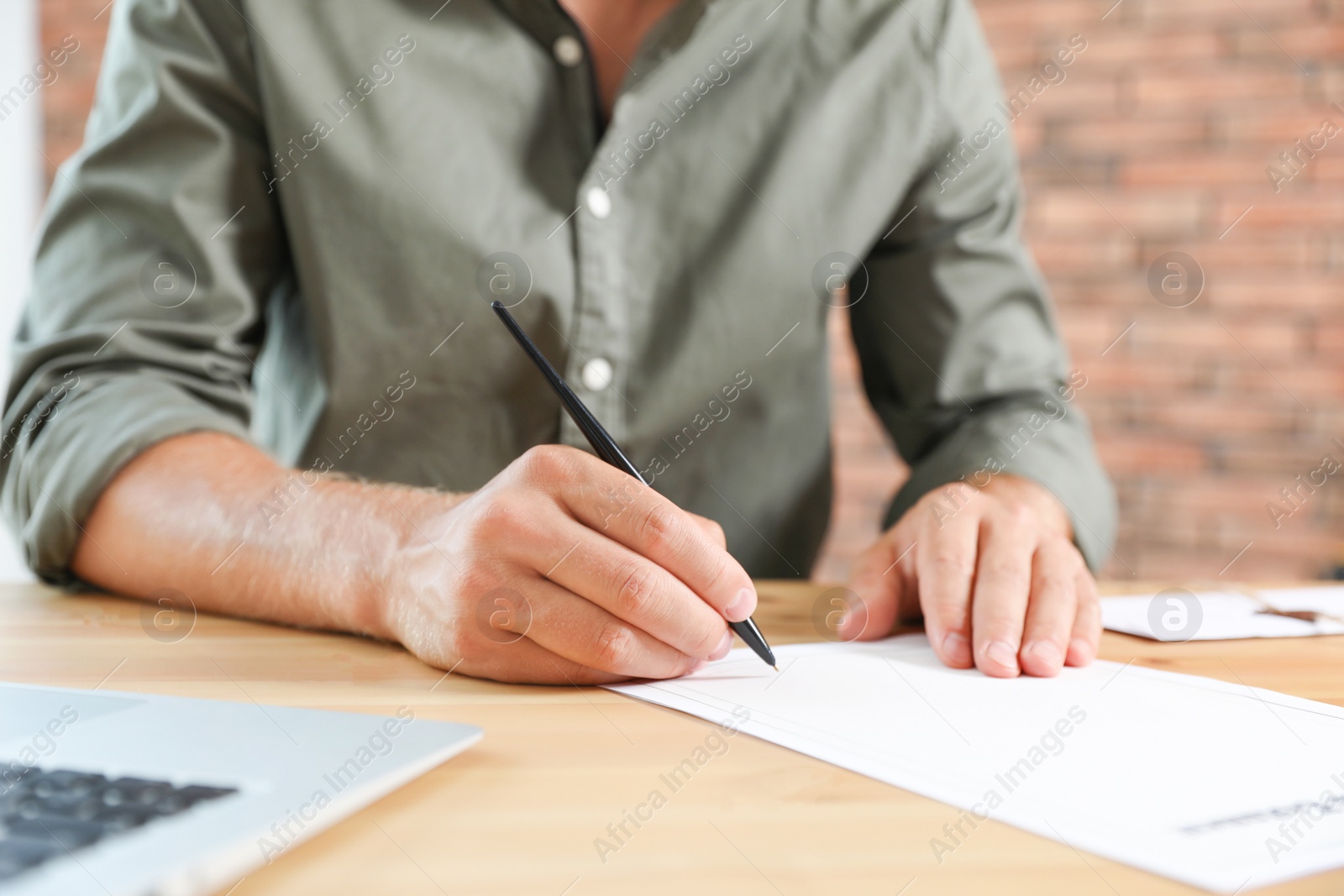 Photo of Male notary signing document at table in office, closeup