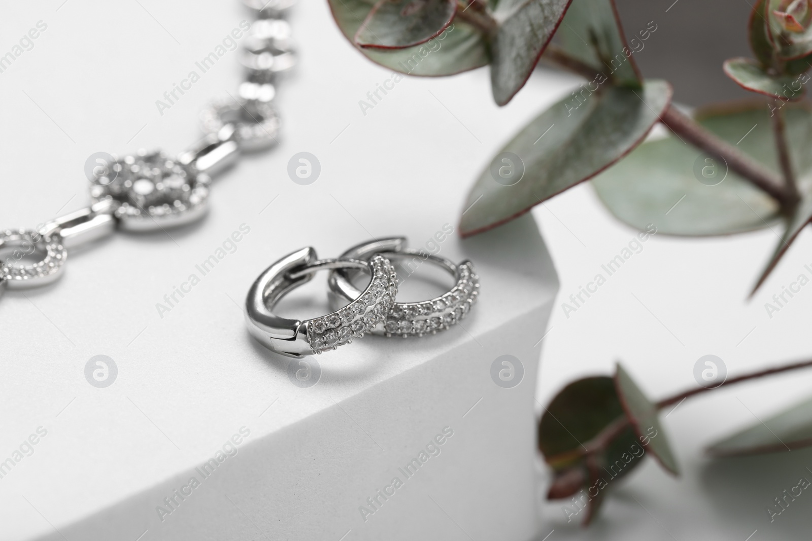 Photo of Beautiful earrings on white podium. Luxury jewelry