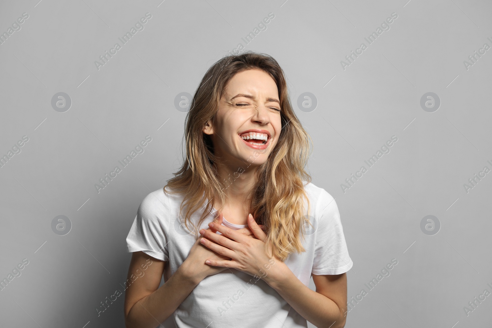 Photo of Cheerful young woman laughing on grey background