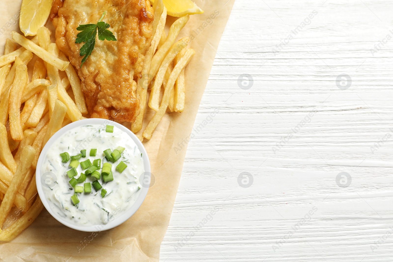 Photo of British traditional fish and potato chips on wooden background, top view with space for text