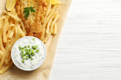 Photo of British traditional fish and potato chips on wooden background, top view with space for text