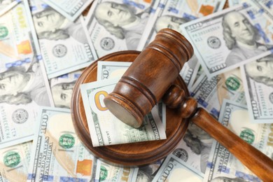 Photo of Wooden judge's gavel on dollar banknotes, closeup