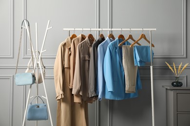 Photo of Rack with different stylish women`s clothes and bags near grey wall