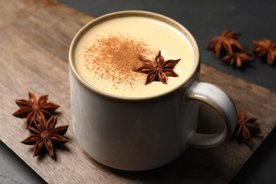 Photo of Delicious eggnog with anise and cinnamon on black table, closeup