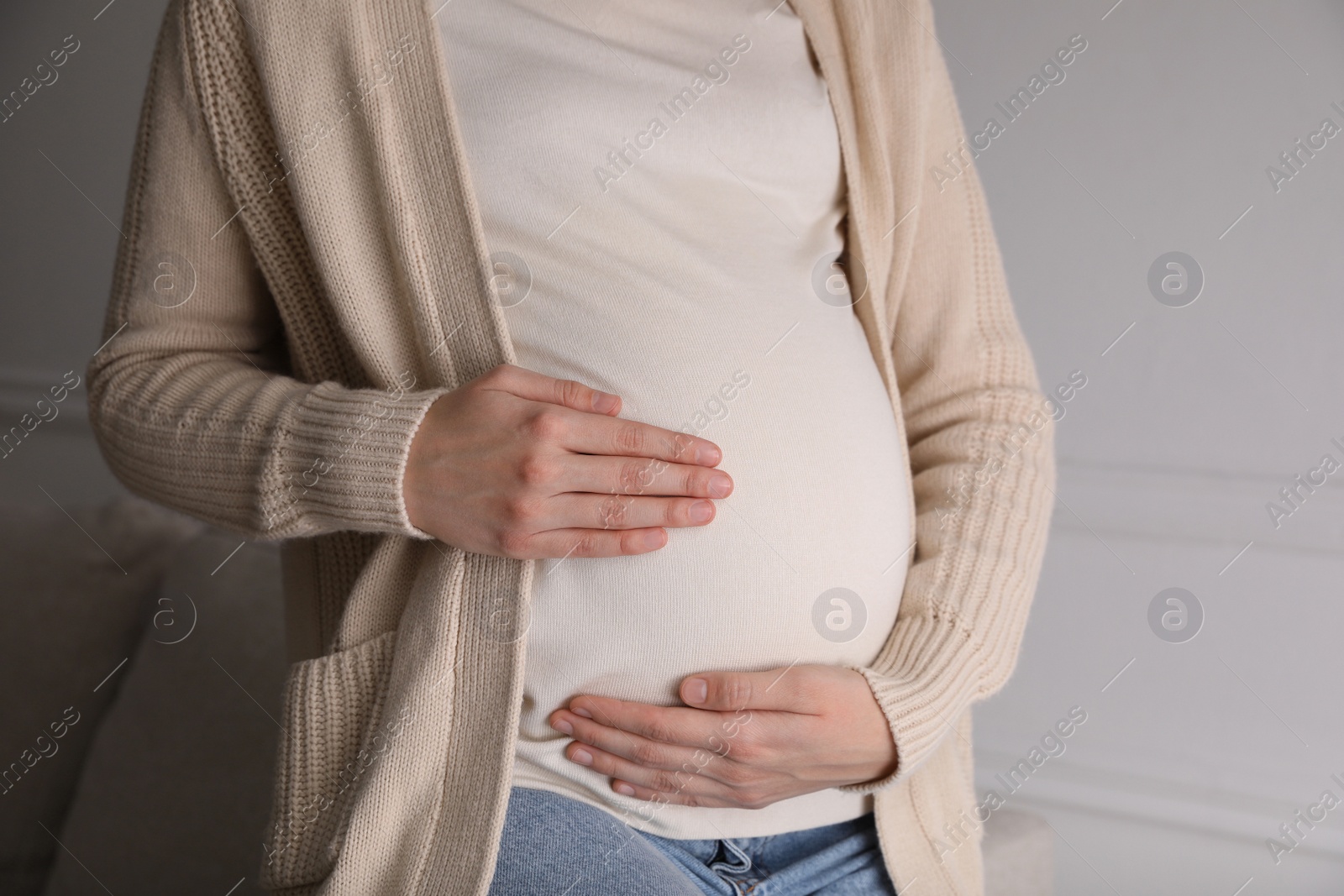 Photo of Young pregnant woman at home, closeup view