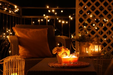 Photo of Beautiful view of garden furniture with pillow and burning candles at balcony