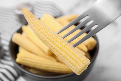 Photo of Pickled baby corn on fork at table, closeup