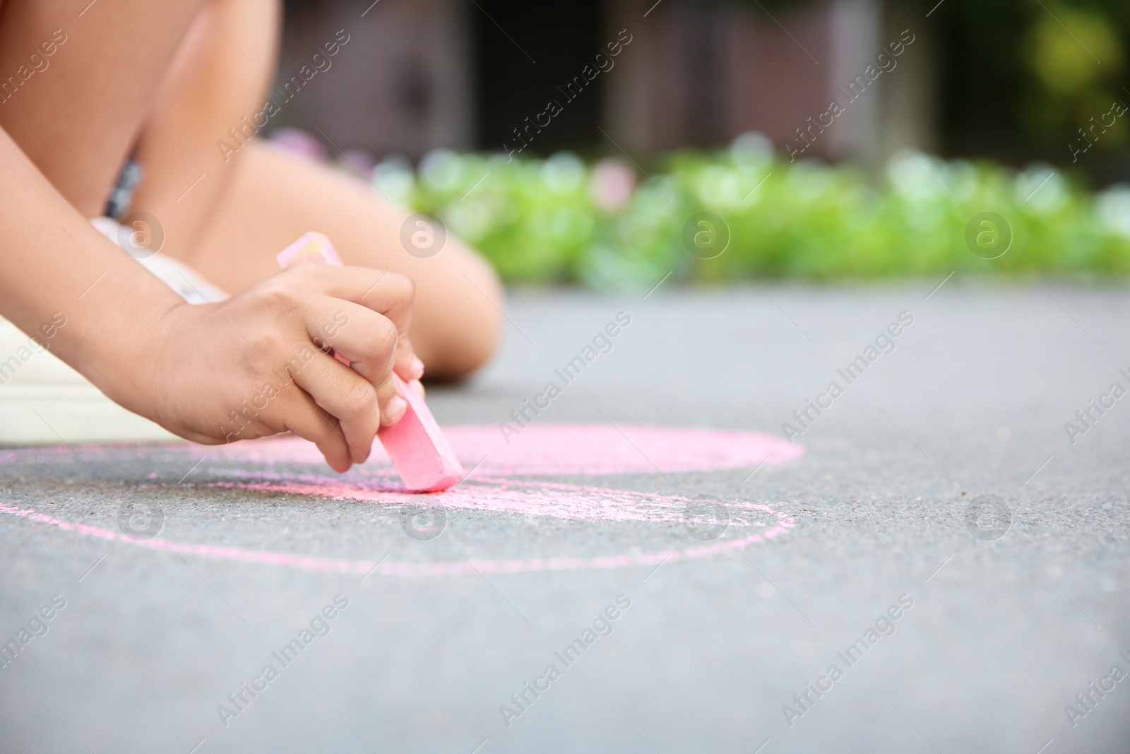 Photo of Little child drawing heart with chalk on asphalt, closeup