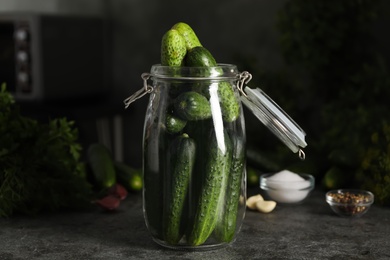 Pickling jar with fresh cucumbers on dark grey kitchen table, closeup