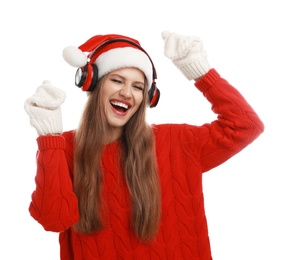 Young woman in Santa hat listening to Christmas music on white background