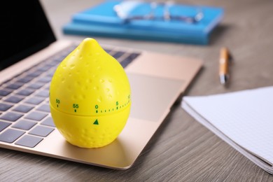 Photo of Kitchen timer in shape of lemon and laptop on wooden table, space for text