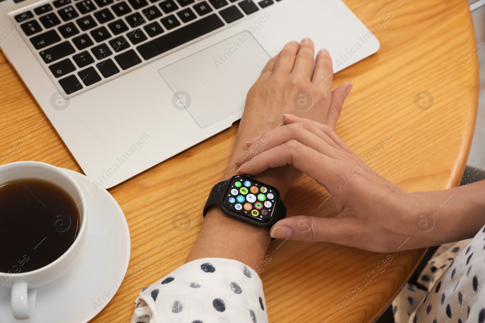 Image of MYKOLAIV, UKRAINE - SEPTEMBER 19, 2019: Woman using Apple Watch at wooden table, closeup