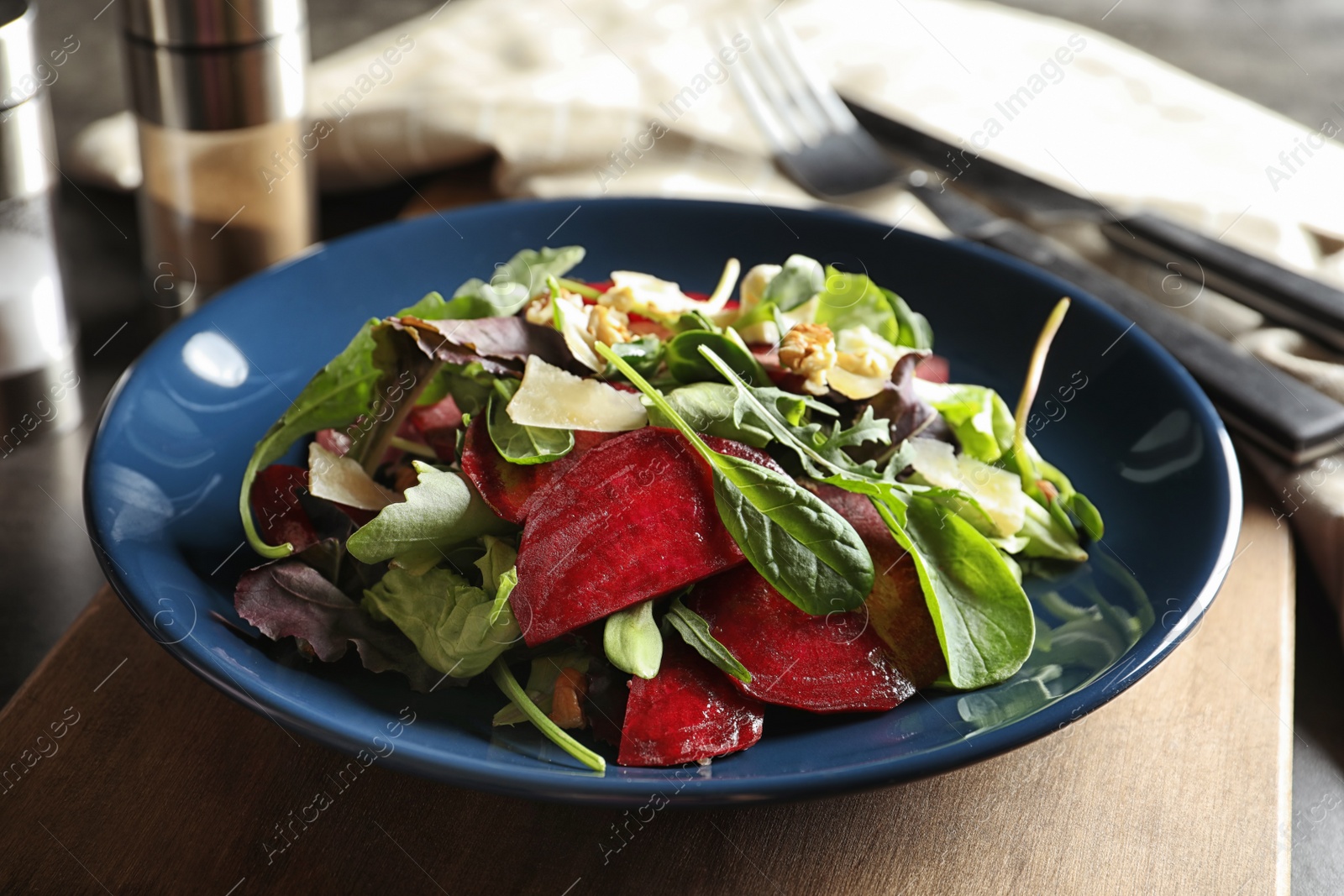 Photo of Plate with delicious beet salad on wooden board, closeup