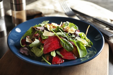 Plate with delicious beet salad on wooden board, closeup