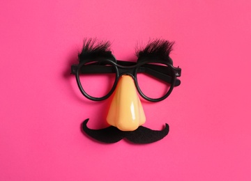 Photo of Funny glasses on pink background, top view
