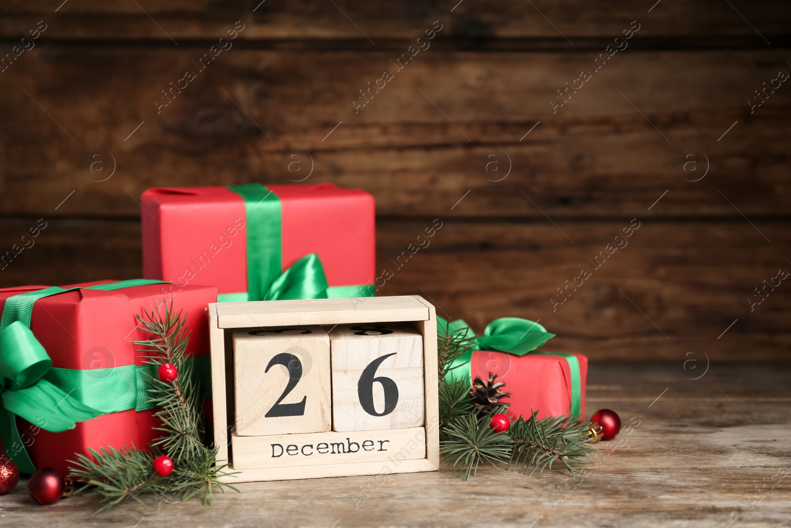 Photo of Block calendar with Boxing Day date near gifts on wooden table. Space for text