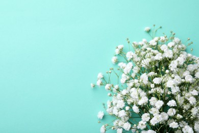 Beautiful gypsophila flowers on turquoise background, top view. Space for text