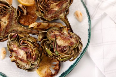 Photo of Plate with tasty grilled artichokes on white table, top view