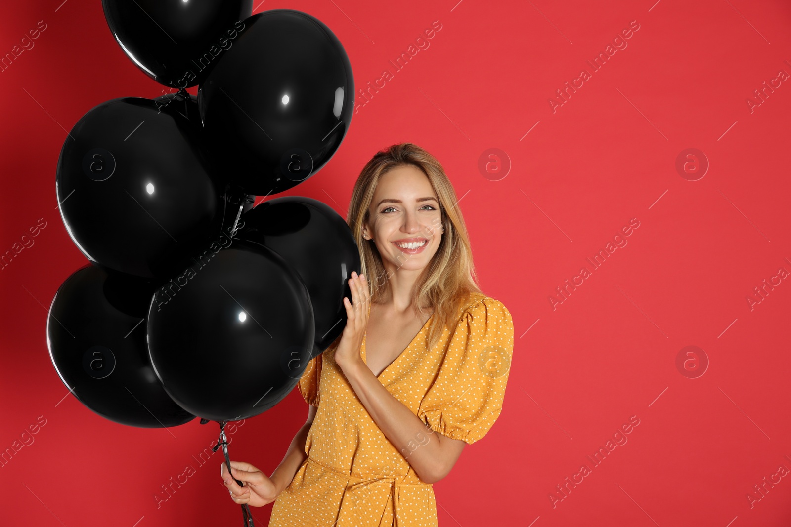 Photo of Happy young woman with balloons on red background, space for text. Black Friday Sale