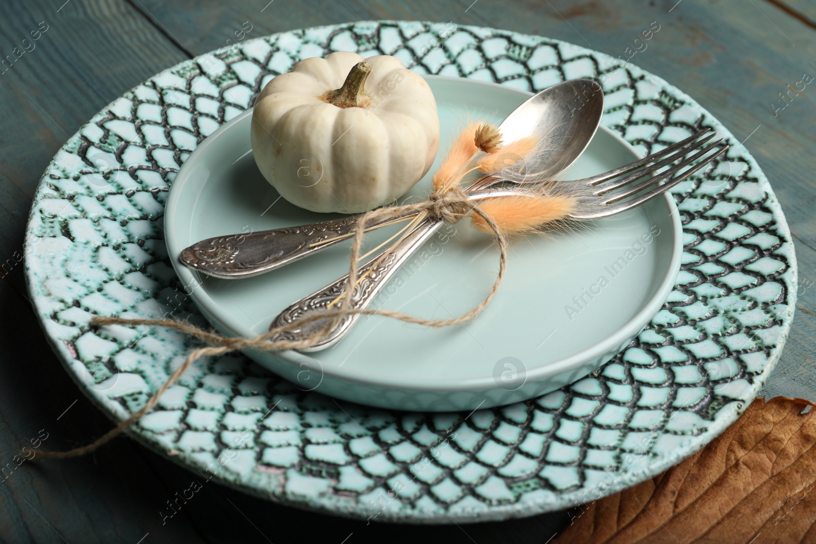 Photo of Autumn table setting with pumpkin on blue wooden background, closeup