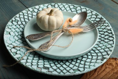 Autumn table setting with pumpkin on blue wooden background, closeup