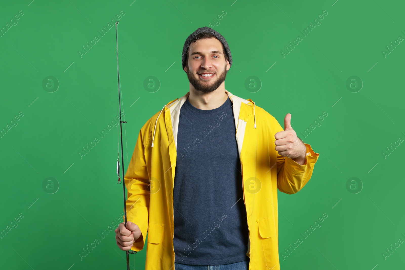 Photo of Fisherman with fishing rod showing thumb up on green background