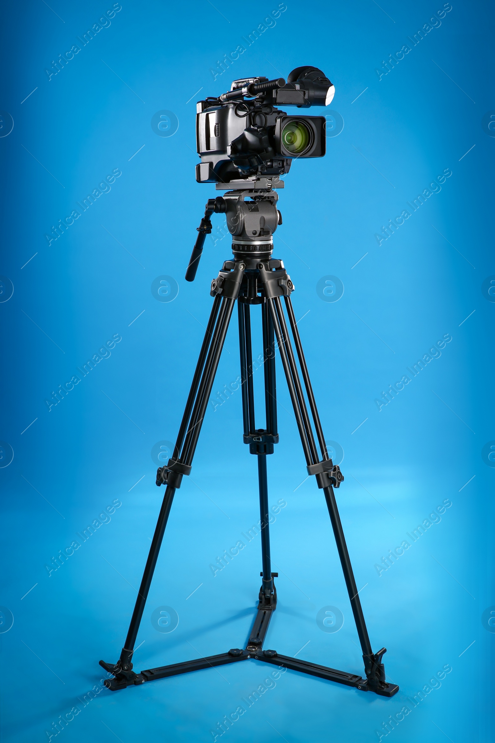 Photo of Modern professional video camera on blue background