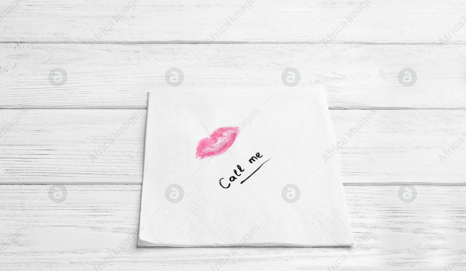 Photo of Paper napkin with lipstick mark and words CALL ME on wooden background. Space for text