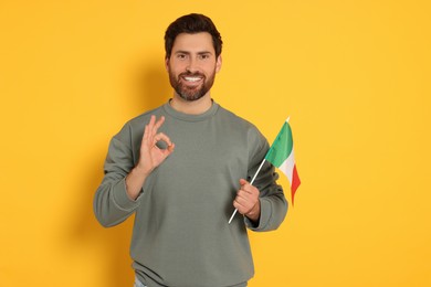 Man with flag of Italy showing ok gesture on yellow background