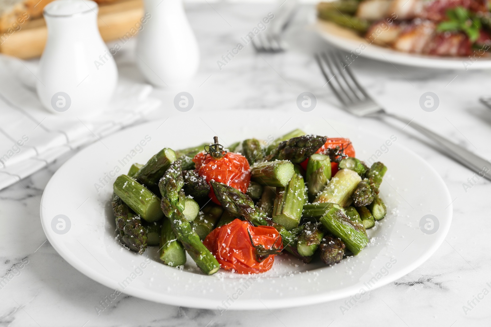 Photo of Oven baked asparagus with cherry tomatoes on white plate