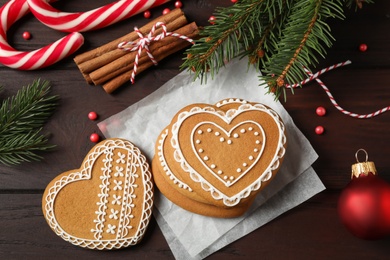 Photo of Flat lay composition with tasty heart shaped gingerbread cookies and Christmas decor on wooden table