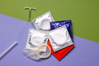 Photo of Condoms and intrauterine device on color background, flat lay. Choosing birth control method